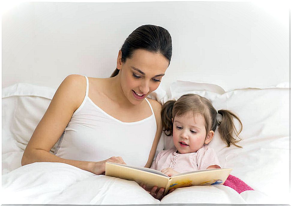 Mother and little girl are reading in bed