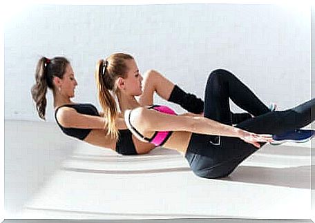 Two girls perform exercises for the abdominals.