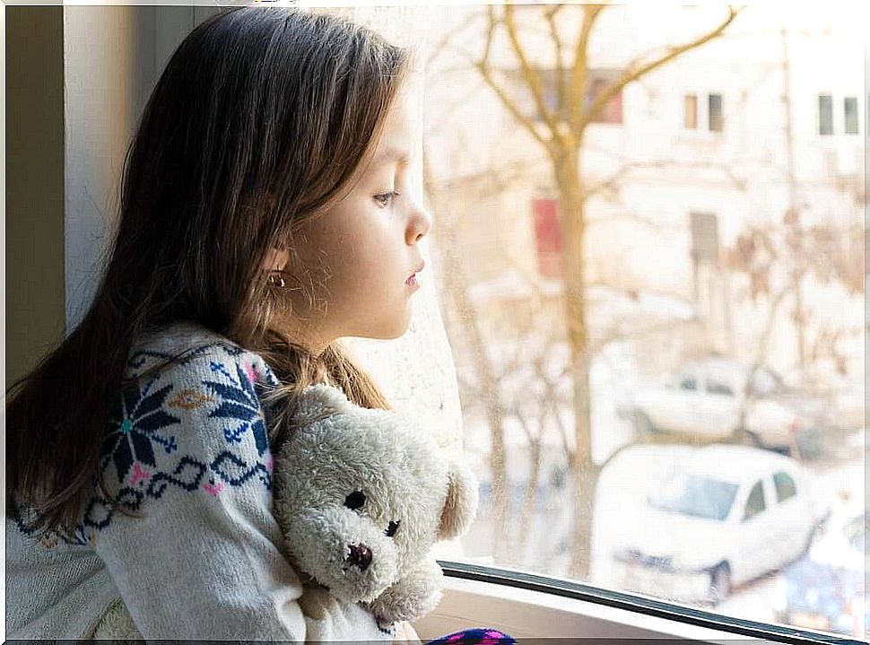 Little girl with teddy bear at the window