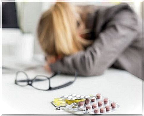 Migraine tablets and girl with head on desk