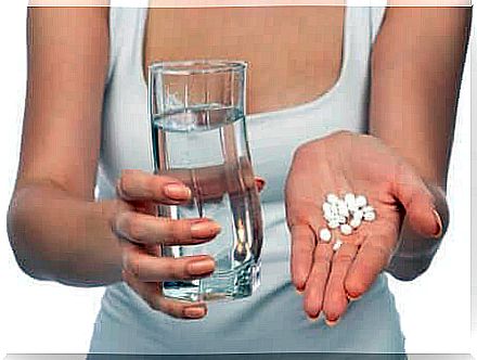 Hands with glass of water and pills.