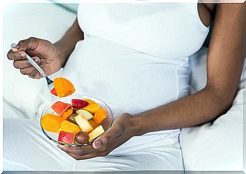 Pregnant woman eating fruit.