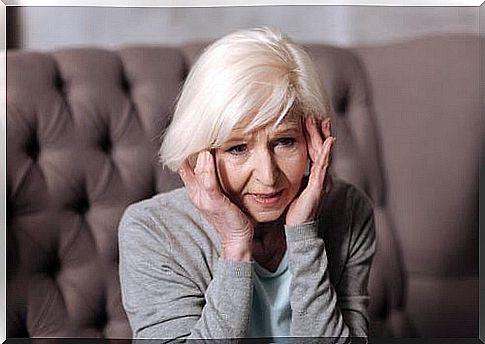 Elderly woman with hands on her temples