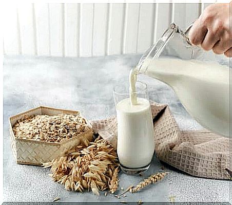 Woman pours oat milk from a jug.